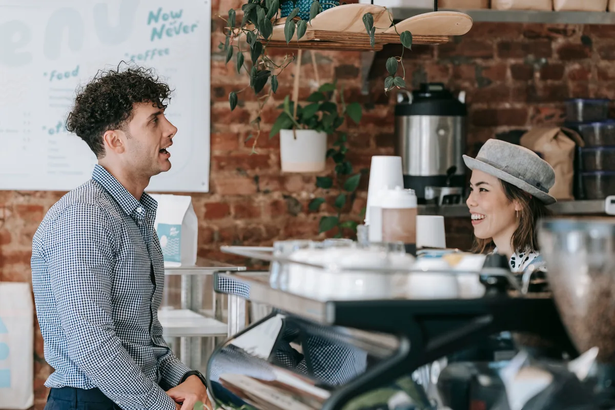 Een medewerker en een bezoeker praten ontspannen bij de koffiebar.